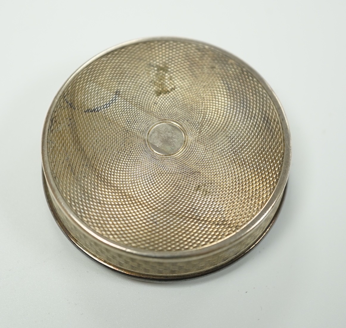 An early 20th century French engine turned white metal and guilloche enamel circular compact with cover, decorated with flowers, 49mm.